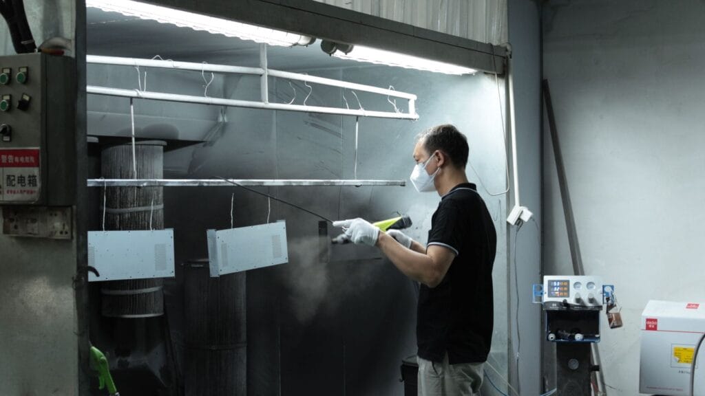 powder coating spray booth worker spraying small panels.jpg